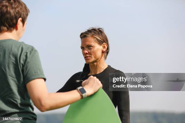 mid adult surfer woman talking with her female coach after wakeboarding training - surfwin review stockfoto's en -beelden