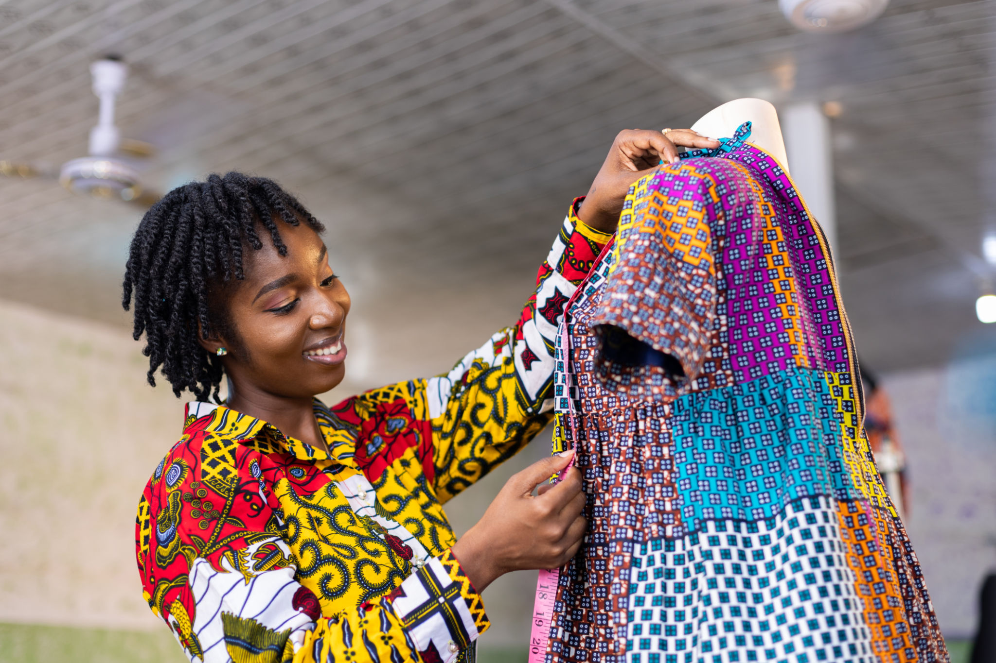 Smiling Ghanaian Dressmaker with African pattern dress in her studio Smiling Ghanaian Dressmaker with African pattern dress in her studio
