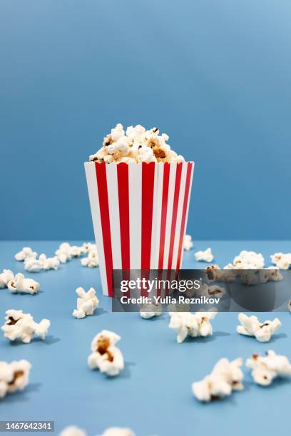 red paper striped bucket with popcorn on the blue background - film studio fotografías e imágenes de stock