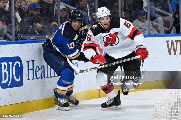 John Marino of the New Jersey Devils skates against Brayden Schenn of the St. Louis Blues at the Enterprise Center on February 16, 2023 in St. Louis,...