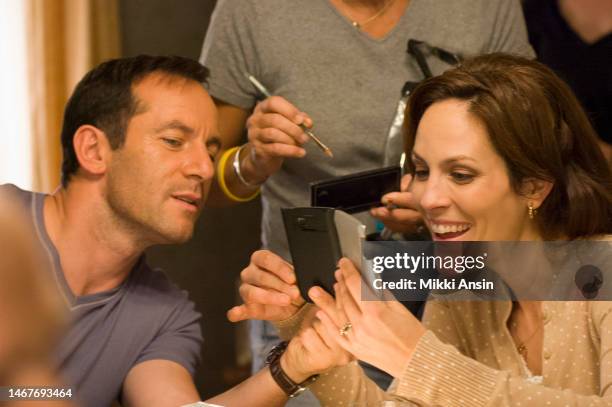 Actor Jason Clarke looks at a smart phone held by fellow cast member Annabeth Gish during the filming of an episode of the cable television series...