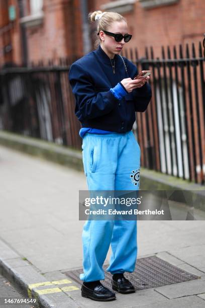 Guest wears black sunglasses, a navy blue zipper bomber coat, blue sport large pants, black socks, black shiny leather loafers , outside 16Arlington,...