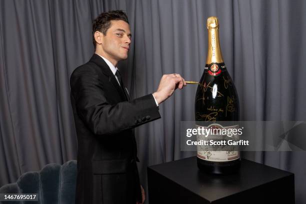 Rami Malek signs the Champagne Taittinger methuselah backstage during the EE BAFTA Film Awards 2023 at The Royal Festival Hall on February 19, 2023...