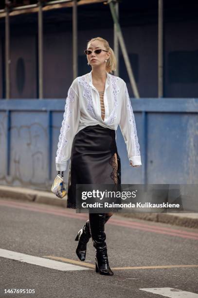 Betty Bachz wearing a black silk skirt with lace, white shirt with chains and lace, and black shiny leather boots outside Christopher Kane during...