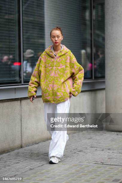 Guest wears a pale gray hoodie sweater, a pale pink and green print pattern sheep hoodie zipper oversized pullover from Supreme, white large pants,...