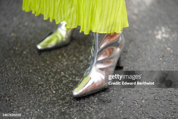 Guest wears a green pleated / accordion puffy long sleeves long dress, silver shiny varnished leather pointed / heels knees boots , outside...