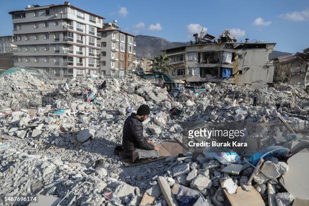 Man prays on debris of collapsed building on February 19, 2023 in Hatay, Turkey. A 7.8-magnitude earthquake hit near Gaziantep, Turkey, in the early...
