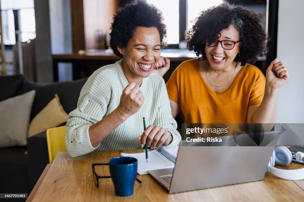 Two excited mature woman looking at a laptop