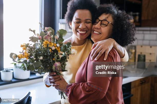 mature woman giving flowers to her wife - överlämna bildbanksfoton och bilder