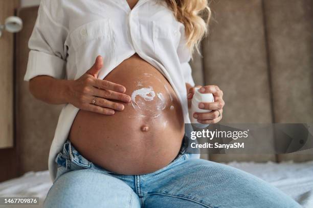 woman applying moisturizer on pregnant belly - stretch mark stock pictures, royalty-free photos & images