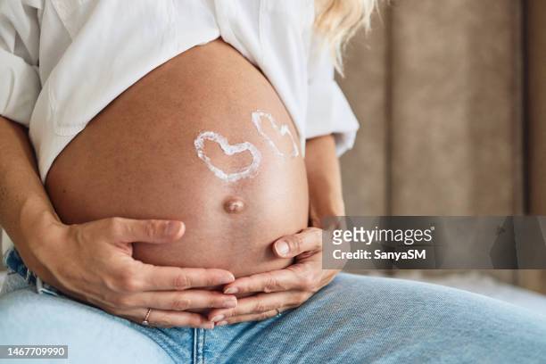 pregnant woman embracing her belly - fetus heart stock pictures, royalty-free photos & images