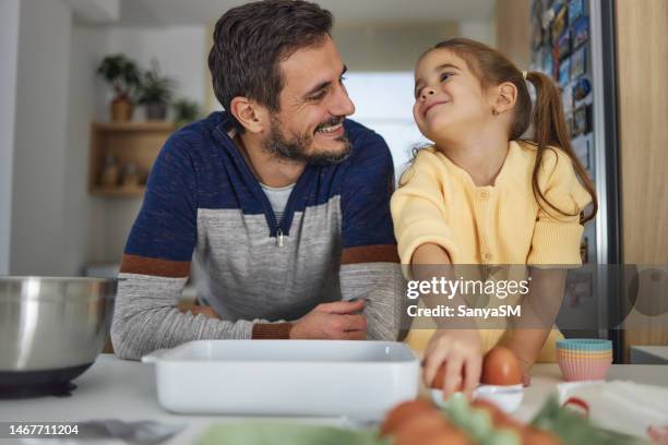 young girl stands at the kitchen table making cakes with her father - daughter cooking stock pictures, royalty-free photos & images