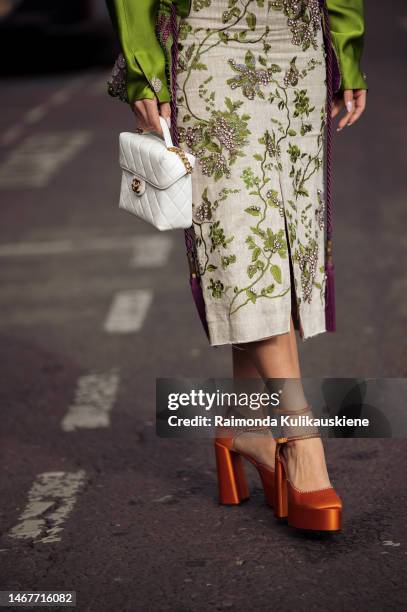 Bettina Looney is seen wearing an off-white dress with embroidery, green jacket, orange shoes and white Chanel bag outside the Erdem show during...