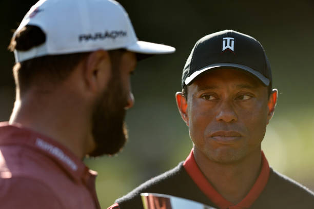 The Genesis Invitational host, Tiger Woods of the United States, presents the trophy to Jon Rahm of Spain after putting in to win The Genesis...