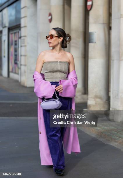 Idalia Salsamendi wears pink coat, off shoulder top with zipper, purple bag, violet corduroy pants, sunglasses outside Feben during London Fashion...