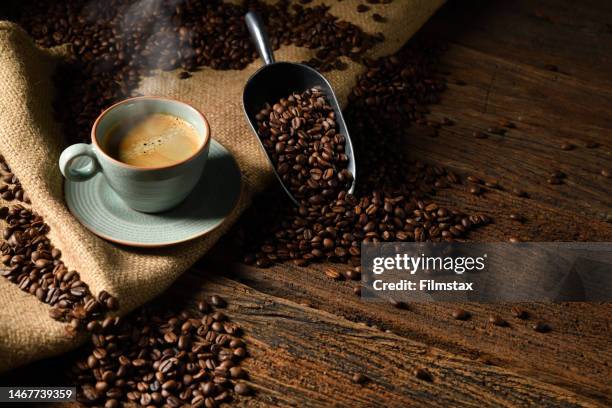 taza de café con humo y granos de café sobre fondo de madera viejo - cafeteria fotografías e imágenes de stock