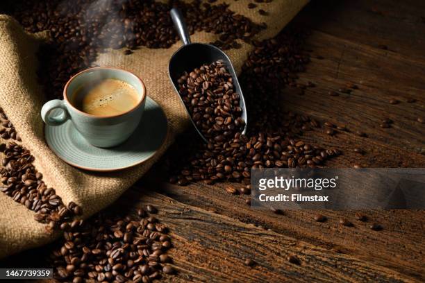 cup of coffee with smoke and coffee beans on old wooden background - café imagens e fotografias de stock