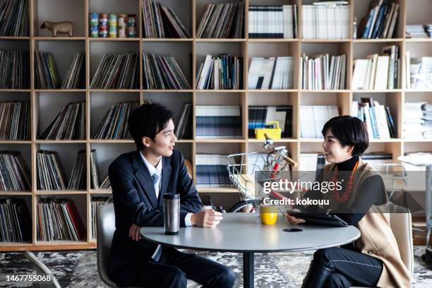 two young entrepreneurs, a man and a woman, discuss their work in a café. - business meeting cafe stock pictures, royalty-free photos & images