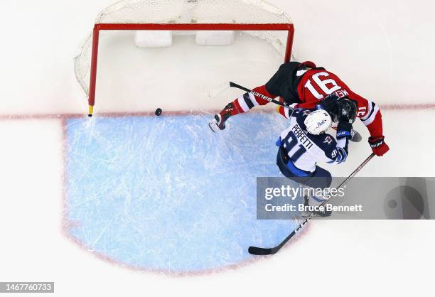 Cole Perfetti of the Winnipeg Jets hits Dawson Mercer of the New Jersey Devils as he scores an empty net goal during the third period at the...