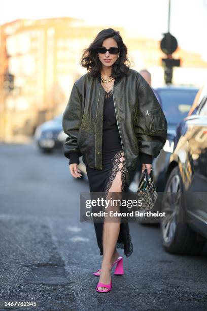 Bettina Looney wears black sunglasses, gold and diamonds earrings, a gold and diamonds large chain necklace, a gold chain necklace, a black lace...