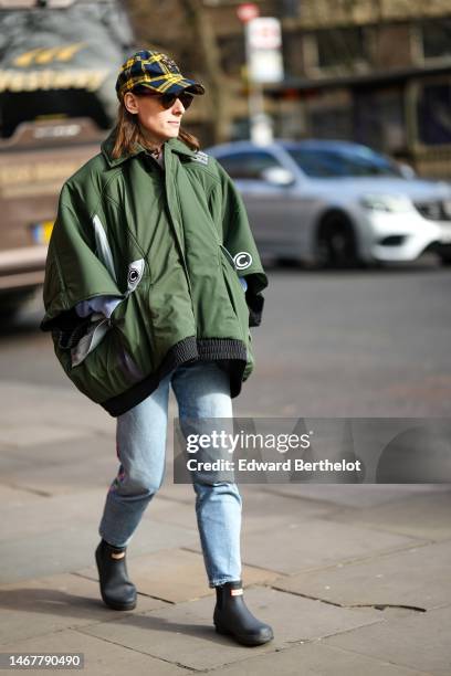 Valentina Mariani wears a navy blue and yellow checkered print pattern with embroidered crystals H pattern cap, black sunglasses from Ray Ban, a dark...