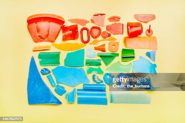 colorful plastic pieces found on beach and lined up on yellow background - plastic pollution beach stock pictures, royalty-free photos & images