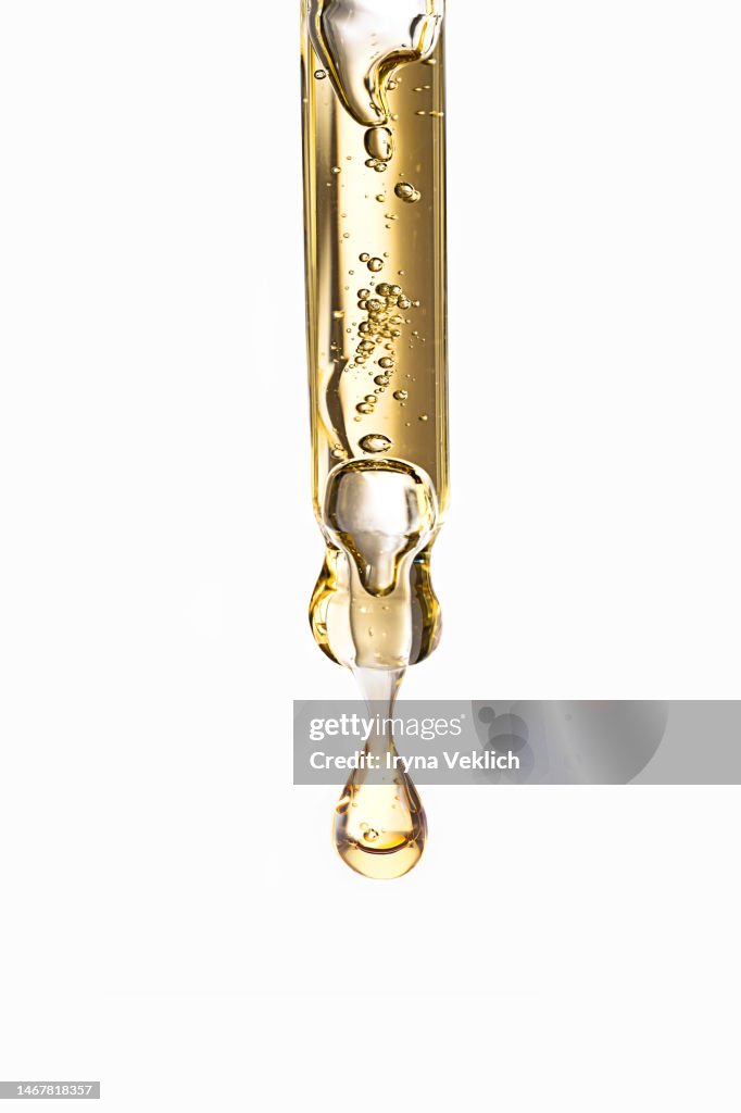 Close-up pipette with Face Serum or Essential Oil with Oxygen Aqua Bubbles and a drop of liquid on a pastel white gray color background.