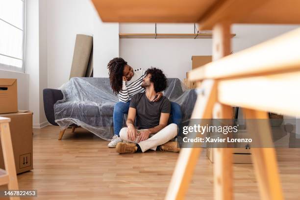 happy multiracial young couple relaxing together in new apartment after relocation. - man with moving boxes authentic stockfoto's en -beelden