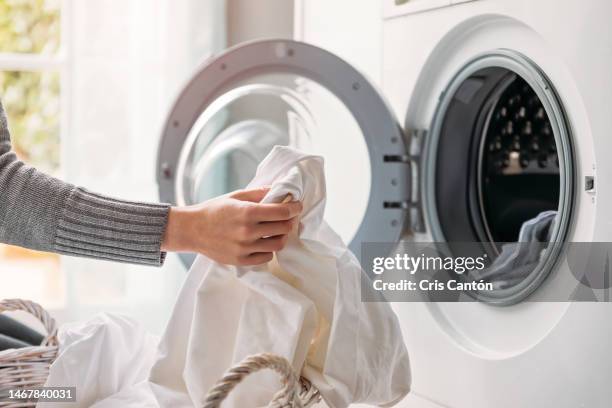 woman loading the washing machine - machine à laver photos et images de collection