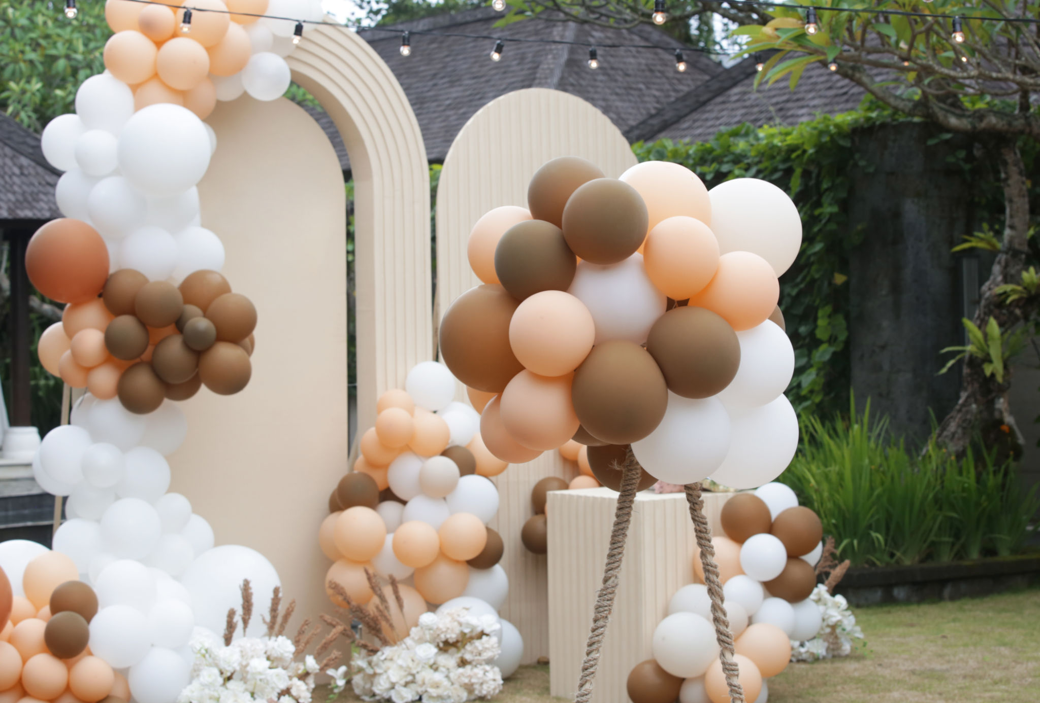 Creative gender neutral baby shower or birthday decoration in the garden. Bohemian style outdoor event set up with balloons. White cream peach caramel balloon arch kit. Creative gender neutral baby shower or birthday decoration in the garden. Bohemian style outdoor event set up with balloons. White cream peach caramel balloon arch kit.