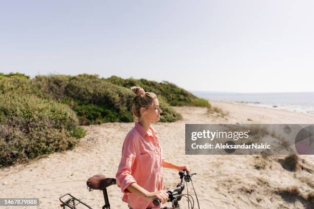 young woman exploring coastline on a bicycle - beach bike stock pictures, royalty-free photos & images