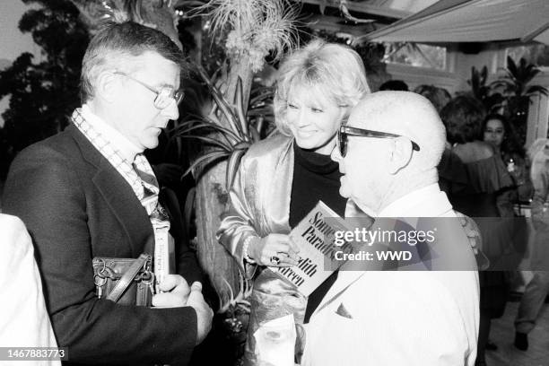 Roddy McDowall, Angie Dickinson, and Irving 'Swifty' Lazar attend a party in Beverly Hills, California, on June 25, 1987.