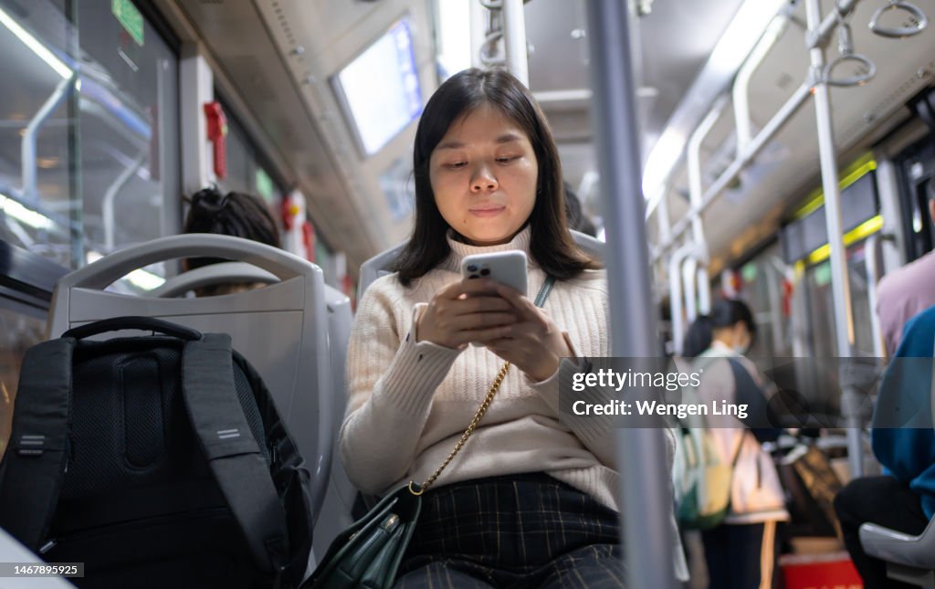 Asian woman using mobile phone on bus