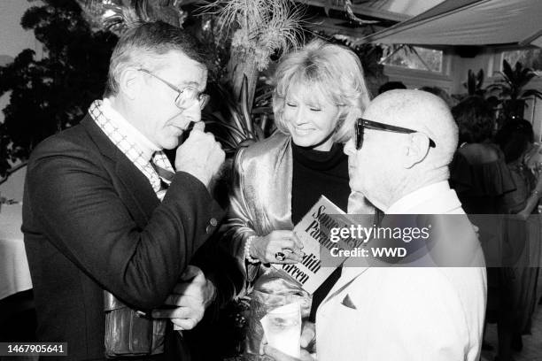 Roddy McDowall, Angie Dickinson, and Irving 'Swifty' Lazar attend a party in Beverly Hills, California, on June 25, 1987.