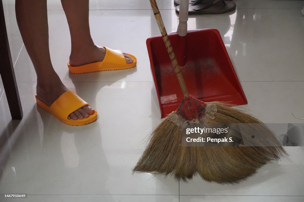 Using Broom Woman Using A Broom To Clean The Floor With A Broom Photo - Getty Images