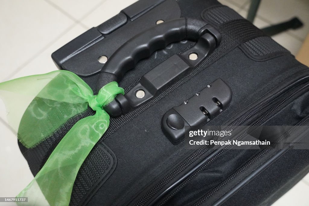 Black luggage, suitcase, baggage tie a green cloth