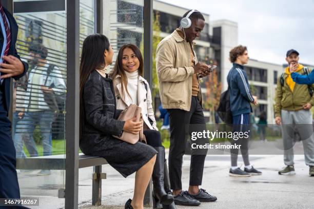 women sitting at bus stop - busshållplats bildbanksfoton och bilder