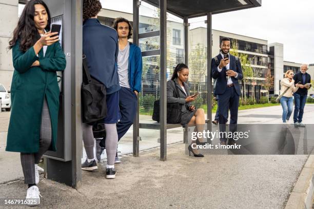 gente parada en la parada de autobús - esperando bus fotografías e imágenes de stock
