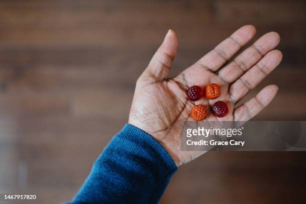 woman holds gummies in palm of her hand - jelly sweet stock pictures, royalty-free photos & images