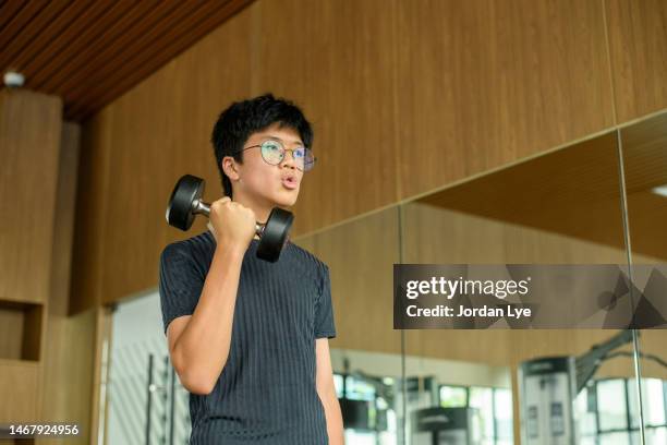 chinese boy workout with dumbbells - skinny teen ストックフォトと画像