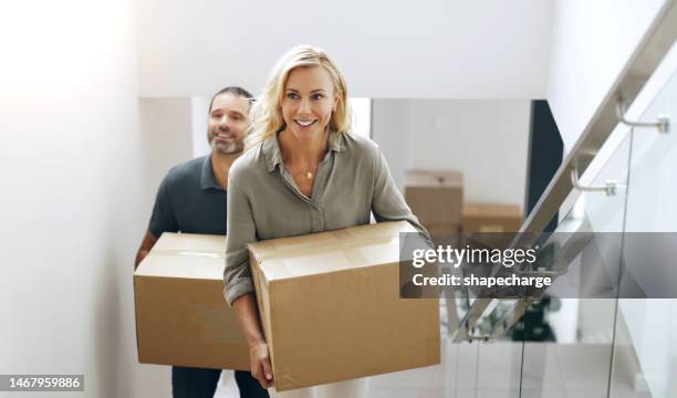 real estate, moving house and a couple carrying a box upstairs while relocating to their new home. property, mortgage or start with a married man and woman unpacking in an apartment as  homeowner - box white flat imagens e fotografias de stock