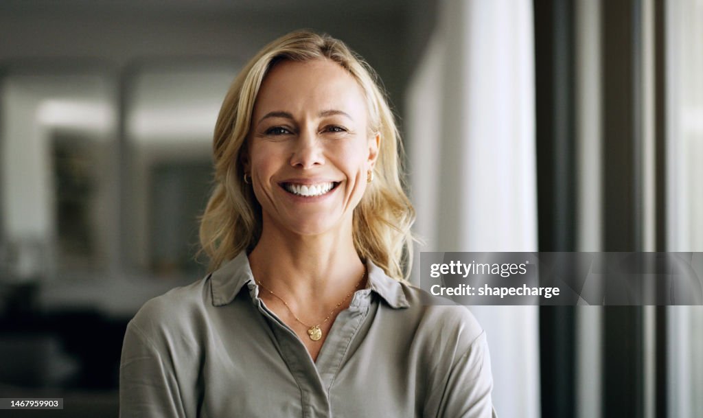 Glückliche, porträtierte und professionelle Frau im Büro mit einer positiven, Führungs- und optimistischen Denkweise. Glück, Lächeln und reife Geschäftschefin, die mit Selbstvertrauen am Arbeitsplatz steht.