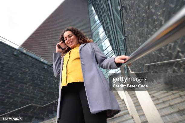 woman  walking while talking on phone - long coat stock pictures, royalty-free photos & images