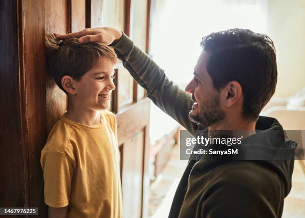 father measuring son's height - high up stock pictures, royalty-free photos & images