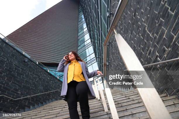 woman  walking while talking on phone - long coat stock pictures, royalty-free photos & images