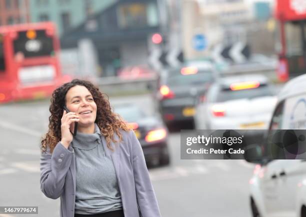 woman  walking while talking on phone - long coat stock pictures, royalty-free photos & images