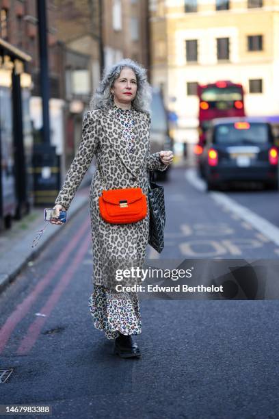 Guest wears silver pendant earrings, a beige and brown leopard print pattern long coat, a white with pink / yellow / blue leopard print pattern high...