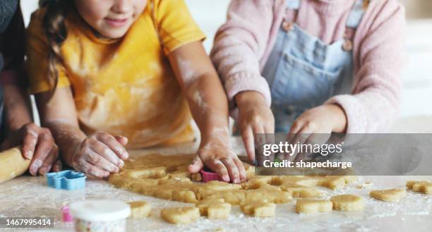 hands, mom and children with baking, cookies and learning together in kitchen with love, bonding and care in house. mother, kids and teaching with teamwork, cooking and helping hand in family home - pastry cutter stockfoto's en -beelden