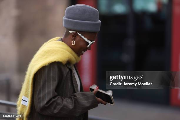 Fashion week guest seen wearing a grey hat, white shades by Marni, a yellow scarf by Jil Sander and a brown oversized blazer and matching pants...