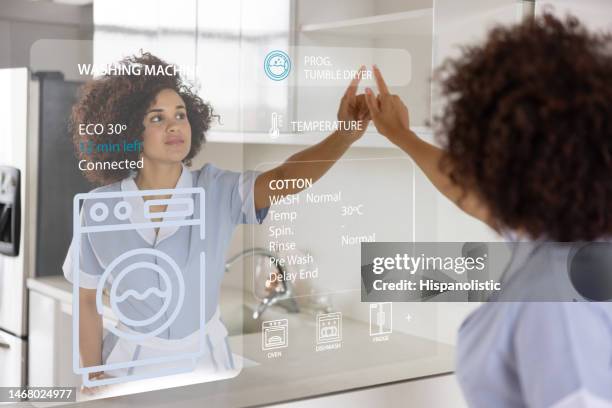 cleaner working at a smart home and programing the washing machine - future home technology stock pictures, royalty-free photos & images